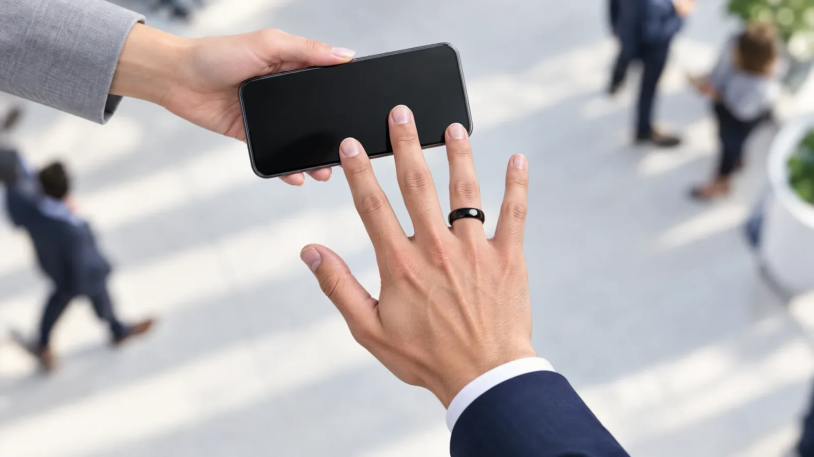 A hand wearing the ring taps another person's phone at an event